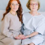 Happy pleasant elderly women in eyeglasses touching hands and looking at camera while smiling